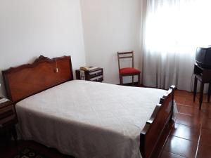 a bedroom with a bed and a television and a chair at Pensão São Jorge in Caldas de São Jorge