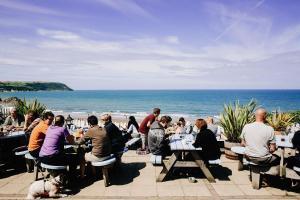 a group of people sitting at tables near the beach at Ship Inn in Aberporth