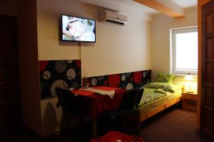 a room with a bed and a table and a tv on the wall at Dj-penzion in Vracov