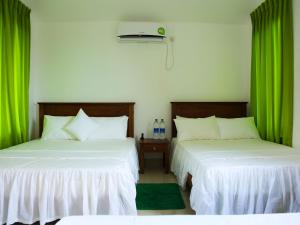 two beds in a room with green curtains at Pasikudah Eco Village Hotel in Pasikuda