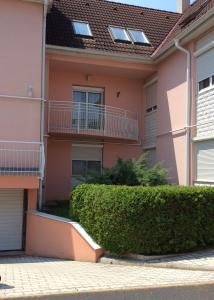 una casa rosa con arbustos delante en Rehab Apartment, en Hévíz
