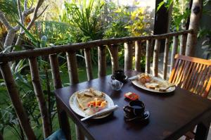 dos platos de comida sentados en una mesa de madera en Willy Homestay, en Uluwatu
