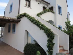 a white building with a staircase covered in ivy at Hotel Resort Nuraghe Arvu in Cala Gonone