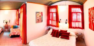 Neve Shalom Hotel في Neve Shalom: غرفة نوم مع ستائر حمراء وسرير في غرفة