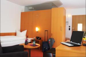 a bedroom with a bed and a desk with a laptop at Hotel Don Bosco in Aschau am Inn