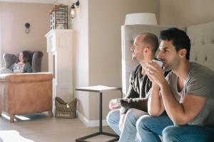 zwei Männer auf einer Couch im Wohnzimmer in der Unterkunft Beach Motel Heiligenhafen in Heiligenhafen