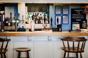 a bar with two chairs and a counter with bottles at Ship Inn in Aberporth