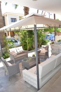 a patio with an umbrella and couches and chairs at Marianna Hotel Apartments in Limassol