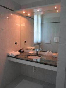 baño con lavabo y espejo grande en Hotel La Villa, en Gravedona