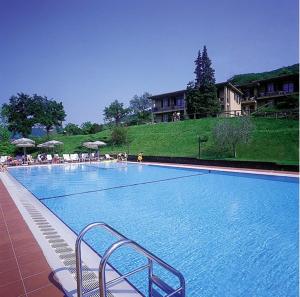 a large swimming pool with chairs and umbrellas at Residence Corte Camaldoli in Garda