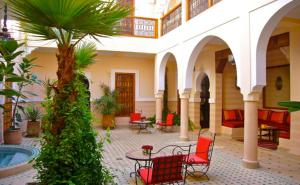 einen Innenhof mit Stühlen und einem Tisch in einem Gebäude in der Unterkunft Riad Rabahsadia in Marrakesch