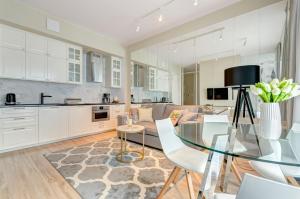 a kitchen and a living room with a glass table at Dom & House - Apartamenty Nowe Orłowo in Gdynia