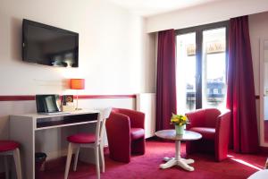 een hotelkamer met rode stoelen, een bureau en een raam bij Hotel des 4 Soeurs in Bordeaux