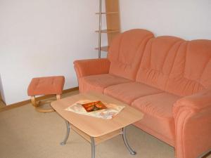 salon z pomarańczową kanapą i stolikiem kawowym w obiekcie Ferienwohnung w mieście Dierkow