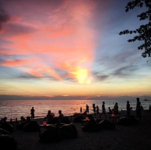 a group of people sitting on the beach at sunset at 15 Palms Beach Resort in Ko Chang