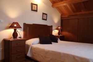 a bedroom with a bed with two lamps on a night stand at Apartamentos Casa Cerolleiro in Castropol