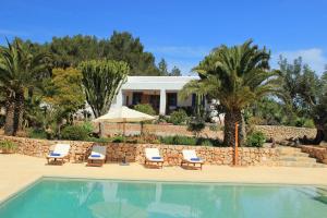 a resort with a swimming pool and chairs and a house at Casa Vilda in Sant Mateu d’Albarca