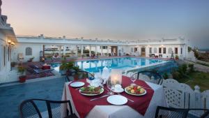 a table with plates of food next to a pool at Aaram Baagh Pushkar by Pachar Group in Pushkar