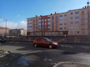 ein kleines rotes Auto, das eine Straße mit Gebäuden entlangfährt in der Unterkunft Leninskiy Prospekt 25 in Norilsk