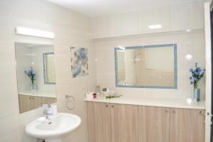 a white bathroom with a sink and a mirror at Marianna Hotel Apartments in Limassol