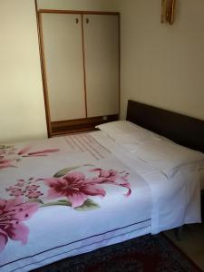 una camera da letto con un letto bianco e fiori rosa di Albergo Luca a Ivrea
