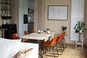 a dining room with a table and orange chairs at B&B De Meerkoet in Linkhout