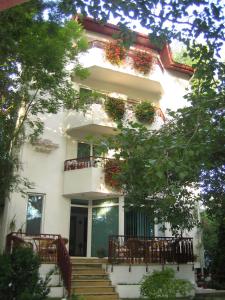 ein weißes Gebäude mit einem Balkon mit Blumen darauf in der Unterkunft Vila Elena in Eforie Nord