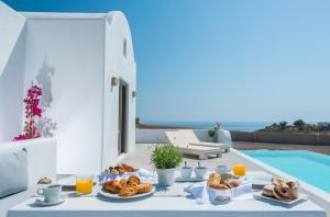 a table with food on it next to a pool at Azar Luxury Villas & Suites in Imerovigli