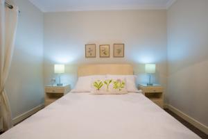 um quarto com uma grande cama branca e 2 candeeiros em Canadian Villa em Ponta Delgada