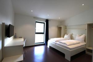 Schlafzimmer mit einem weißen Bett und einem TV in der Unterkunft Neumann's Übernachten in Plankstadt