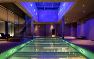 a swimming pool in a building with blue lighting at Einstein St. Gallen in St. Gallen