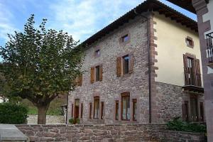 a large stone building with a tree in front of it at Eskolazaharra in Oronoz-Mugaire