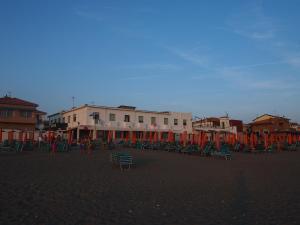 a group of chairs on a beach with buildings at Hotel Aurora in Marina di Cecina