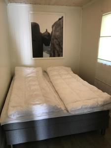 Bett in einem Zimmer mit einem Bild an der Wand in der Unterkunft Guse gård in Kvinesdal