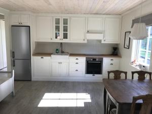 eine Küche mit weißen Schränken, einem Tisch und einem Kühlschrank in der Unterkunft Guse gård in Kvinesdal