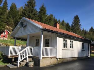 une petite maison blanche avec un toit rouge dans l'établissement Guse gård, à Kvinesdal