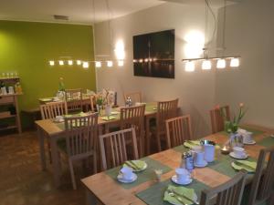 a restaurant with wooden tables and chairs and a green wall at Apartmenthaus Sonnen in Düsseldorf