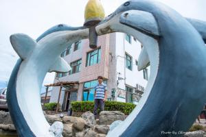 Un ragazzo in piedi dietro una statua di delfini di Love With Dolphin B&B a Magong