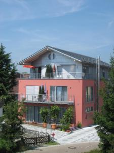 ein großes rotes Gebäude mit Pflanzen auf den Balkonen in der Unterkunft Haus Lorenz, Ferienwohnungen in Immenstaad am Bodensee