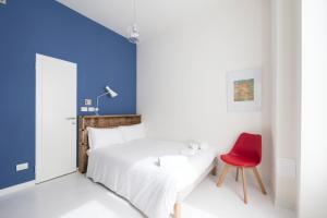ミラノにあるHeart Milan Apartments Duomo SanBarnabaのベッドルーム(白いベッド1台、赤い椅子付)