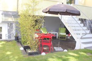 un patio con una mesa roja y sillas bajo una sombrilla en Ferienwohnung Rath, en Colonia