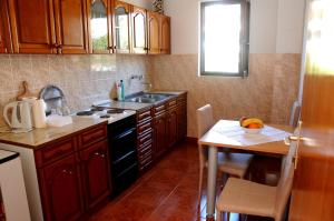 a kitchen with wooden cabinets and a table and a sink at Guest House Smajlaga in Ulcinj