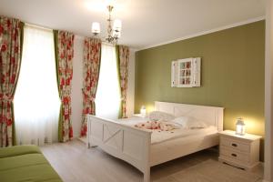 a bedroom with a white bed with green walls and windows at Casa Hermanni in Sibiu