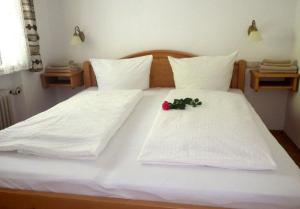 ein Bett mit weißer Bettwäsche und einer Blume darauf in der Unterkunft Farchant-Zugspitze in Farchant