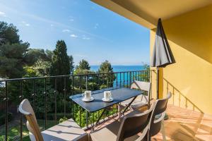 a balcony with a table and chairs and an umbrella at La Résidence du Bailli in Rayol-Canadel-sur-Mer