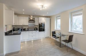 a kitchen with white cabinets and a table and chairs at House of Fisher - Central Point in Basingstoke