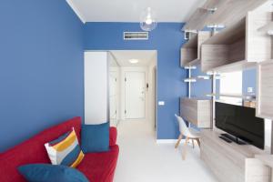 ミラノにあるHeart Milan Apartments Duomo SanBarnabaの赤いソファと青い壁のリビングルーム