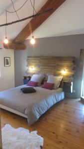 - une chambre avec un grand lit et une tête de lit en bois dans l'établissement A la belle histoire, à Châteauneuf-sur-Isère
