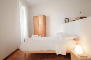 ein weißes Schlafzimmer mit einem Bett mit weißer Bettwäsche und Kissen in der Unterkunft Traditional Studio in Alfama in Lissabon