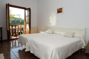 a bedroom with a white bed and a balcony at Hotel Solatorre in Comillas